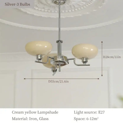 A bauhaus medieval chandelier with three cream yellow glass lampshades and a polished chrome iron frame for living rooms
