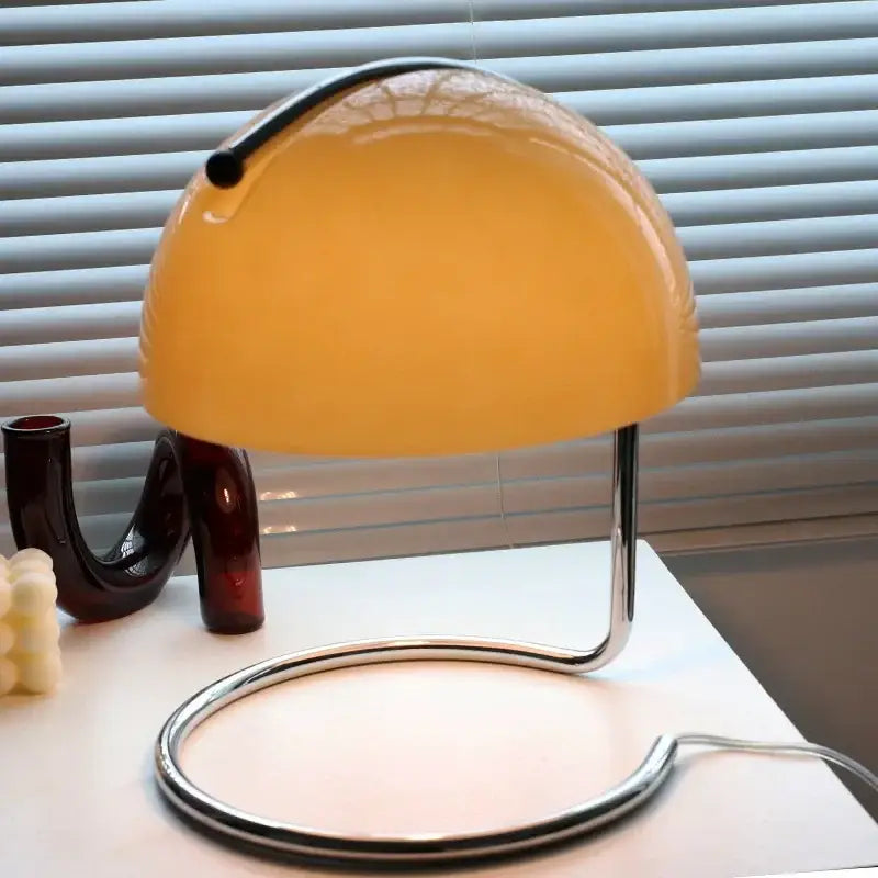 A bauhaus mushroom modern led desk lamp with amber glass dome and chrome base for bedroom aromatherapy use