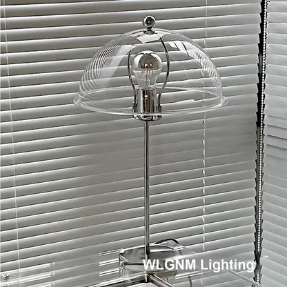 A sleek chrome bauhaus mushroom table lamp with clear glass dome and exposed bulb for bedroom night light