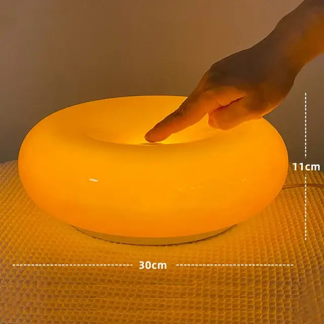 A bauhaus orange glass style glass table lamp with smooth rounded edges and warm orange light for bedroom use