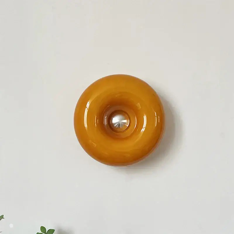 Bauhaus orange glass table lamp featuring a glossy amber glass wall sconce with central metallic accent for bedroom use
