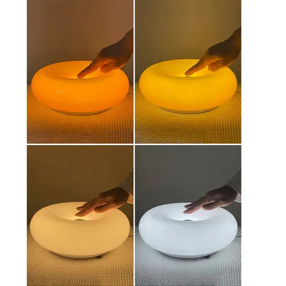 A sleek bauhaus orange glass table lamp with a ring shape and translucent body emitting warm or cool light