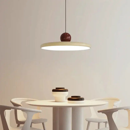 Minimalist bauhaus saucer chandelier with matte cream circular shade and glossy burgundy spherical top for dining room