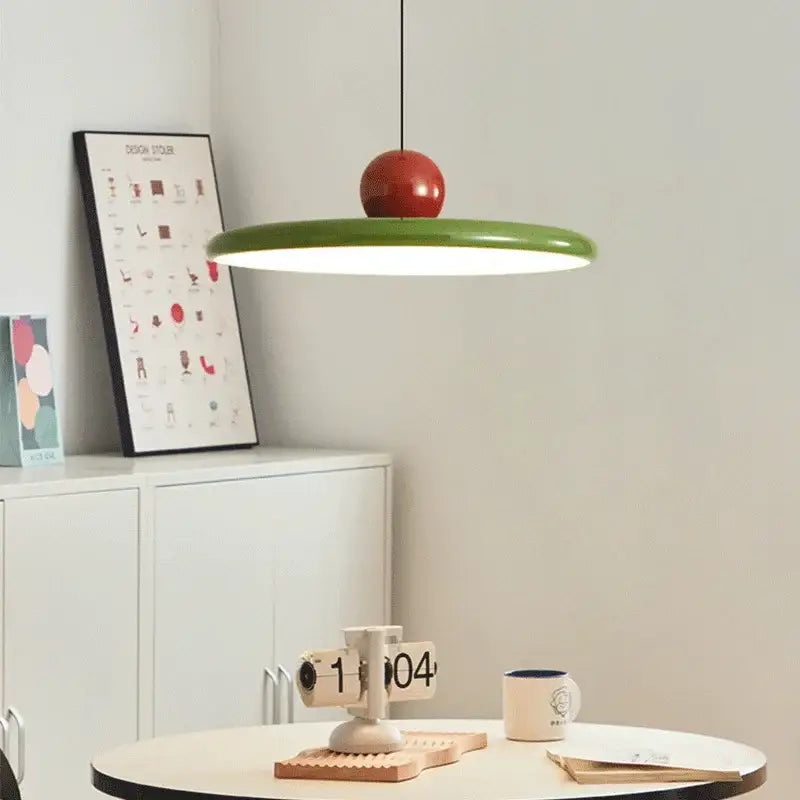 A modern bauhaus saucer chandelier with a vibrant green circular shade and glossy red spherical top for dining rooms