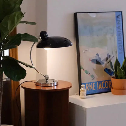 Black metal desk lamp with sleek curved arm and polished chrome base for bauhaus vintage desk office or bedroom use