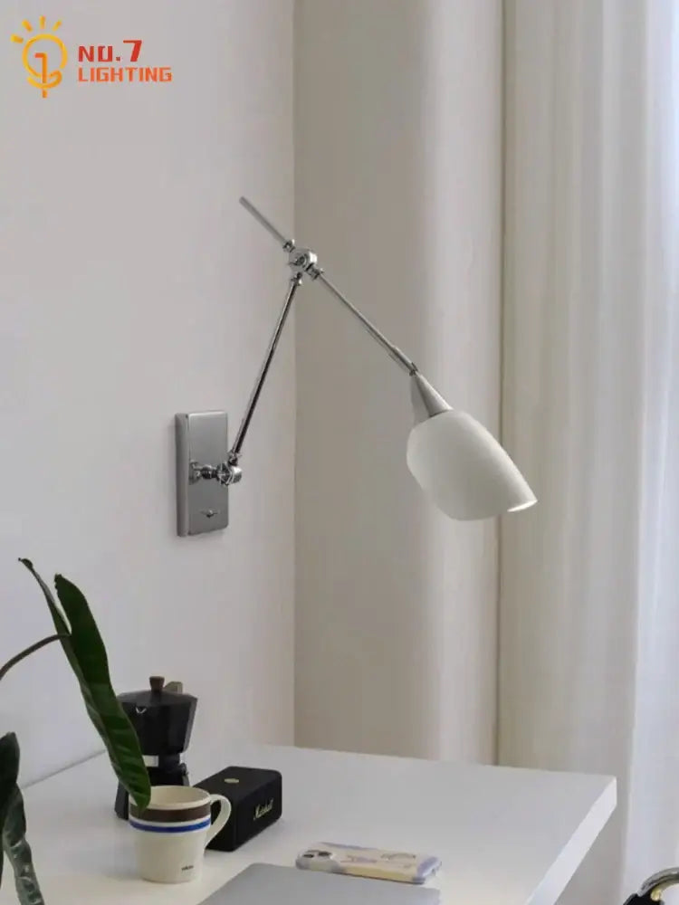 A bauhaus vintage swing arm wall lamp with a chrome articulated arm and white ceramic shade for living rooms