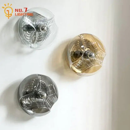 Three spherical bauhaus wavy glass wall lamps with metallic interiors and polished chrome centers for bedroom lighting