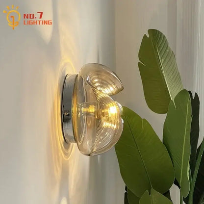 Clear glass shell wall lamp with chrome base featuring bauhaus wavy glass design for bedroom lighting