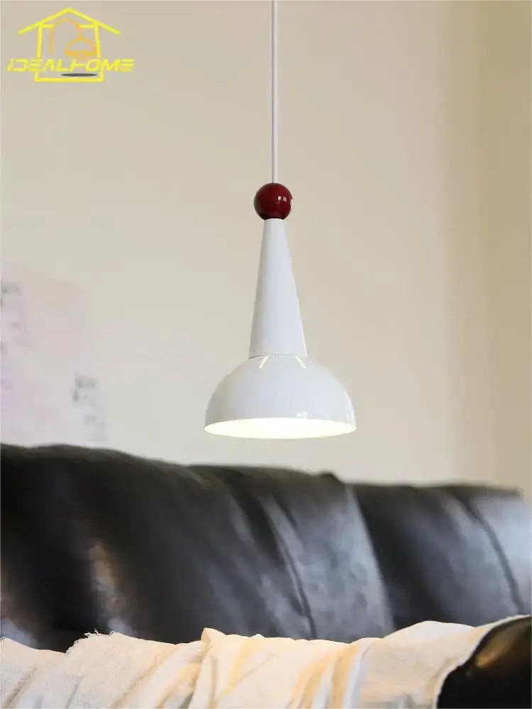 A bauhaus colorful led pendant light with a sleek white conical shade and glossy red spherical accent for kitchen use