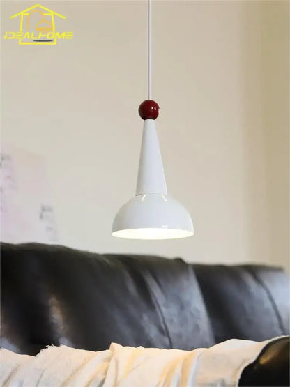 A bauhaus colorful led pendant light with a sleek white conical shade and glossy red spherical accent for kitchen use