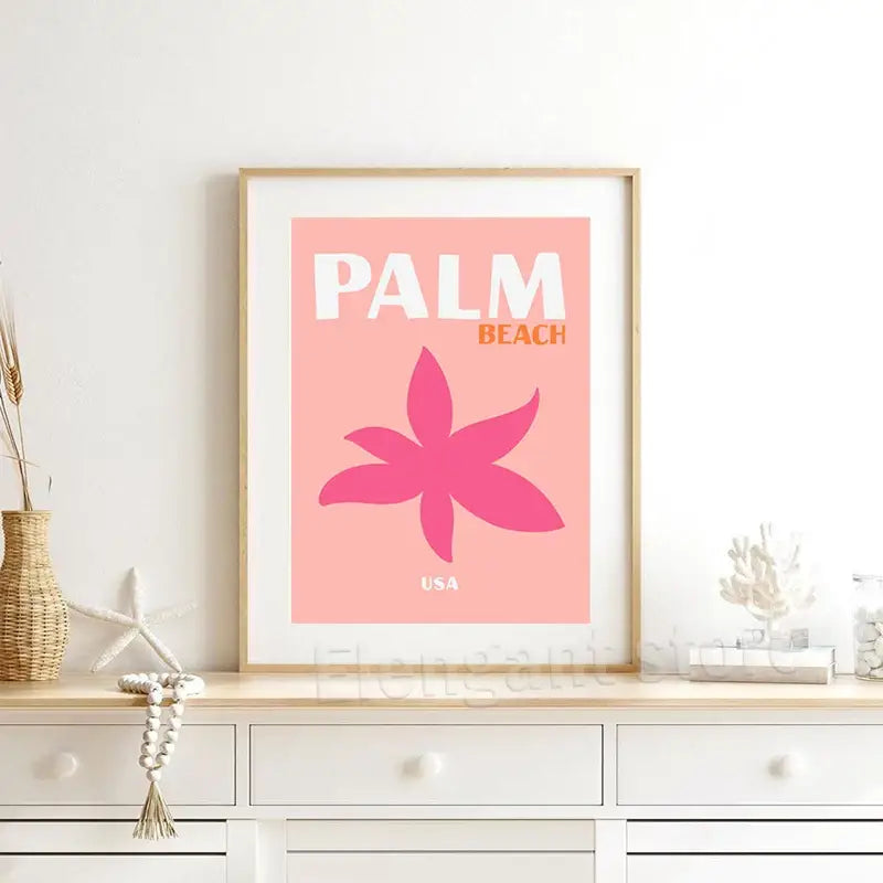 A framed DecorBites™ beach travel poster with pink background and magenta flower perfect for living room decor