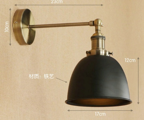 Black industrial-style bedroom wall sconce with brass accents and adjustable arm for versatile lighting