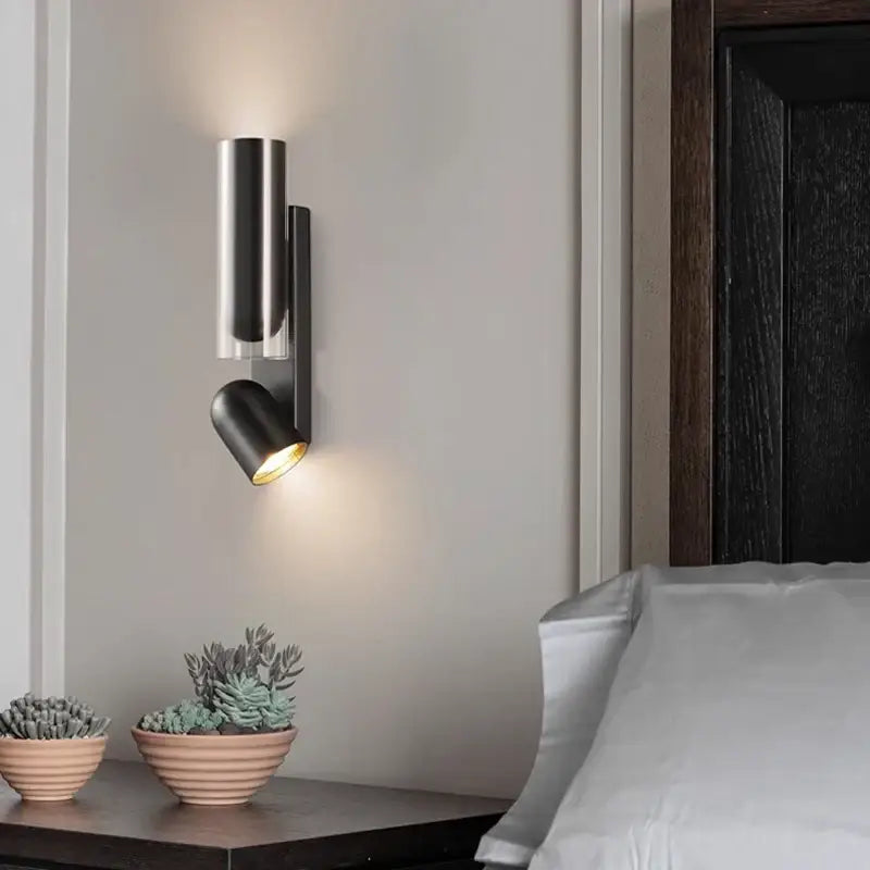 Modern brushed stainless steel bedroom wall reading lamp with sleek cylindrical body and adjustable spotlight head
