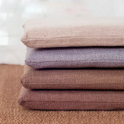 Stack of four beige and brown non-slip decorbites linen seat cushions made of textured woven fabric for dining chairs