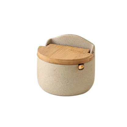 Beige ceramic seasoning jar from decorbites with speckled design, bamboo lid, and gold-tone metal clasp for kitchen use