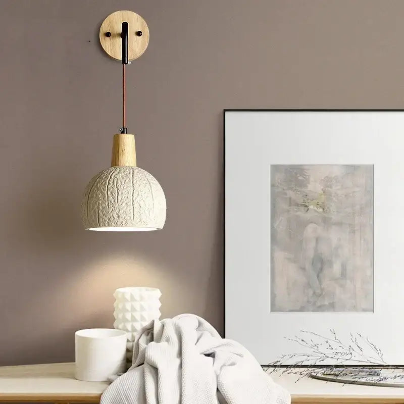 Beige ceramic wall sconce with textured surface, wooden top, circular mount, and pull chain switch for bedroom use