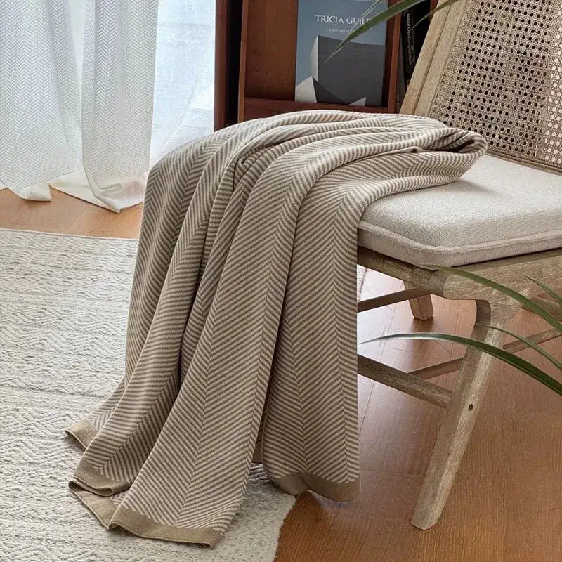 Beige and cream herringbone knit throw blanket draped over wooden chair decorbites cozy striped living room throw