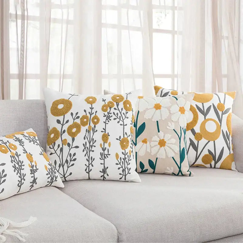 Set of four pillow covers with decorbites daisy floral geometric patterns in mustard yellow white and teal on soft fabric