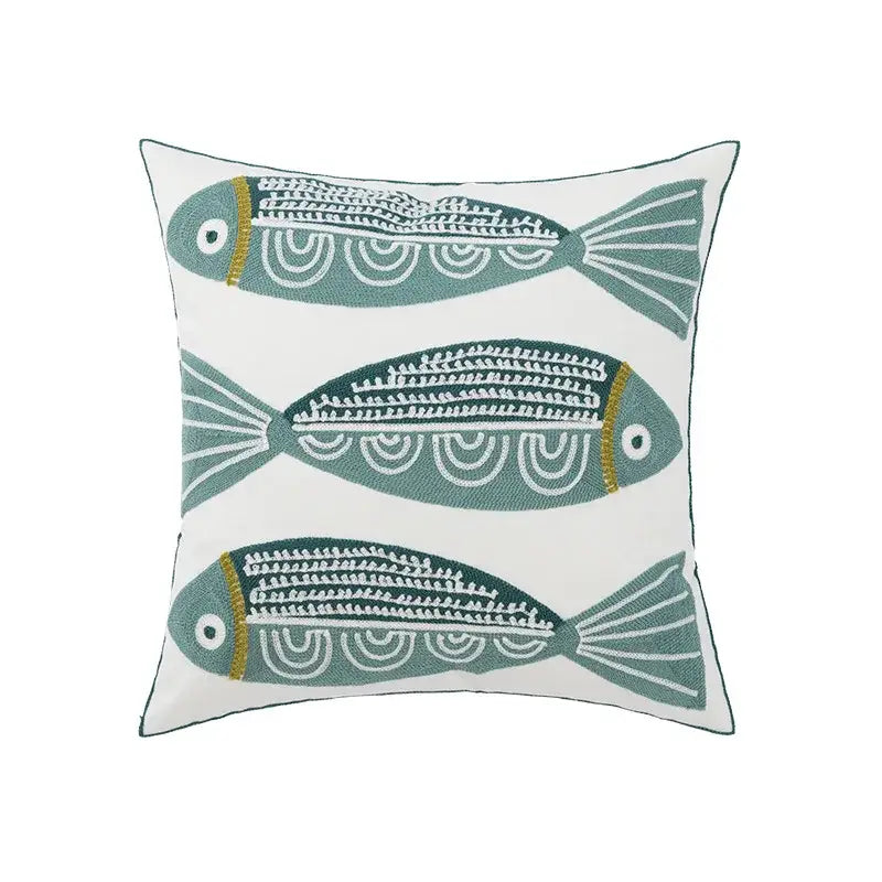 White cushion pillow cover with embroidered daisy floral design featuring three teal fish with white and gold details