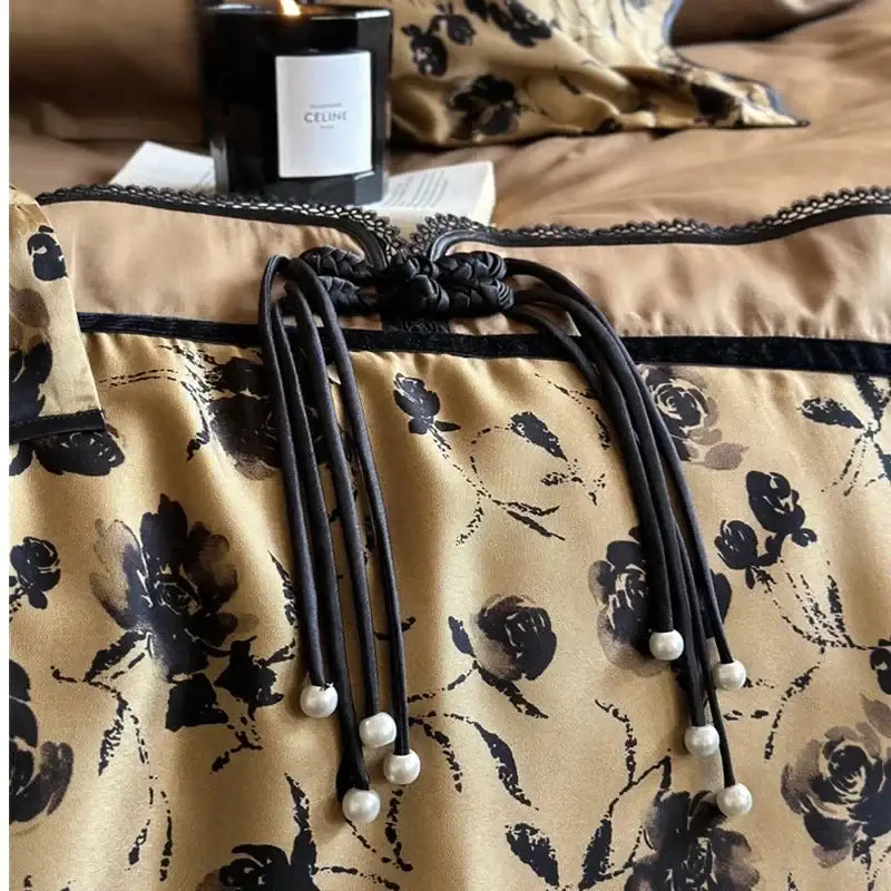 Black braided cord with pearl-tipped ends and decorative knot on beige floral decorbites cotton patchwork bedding set