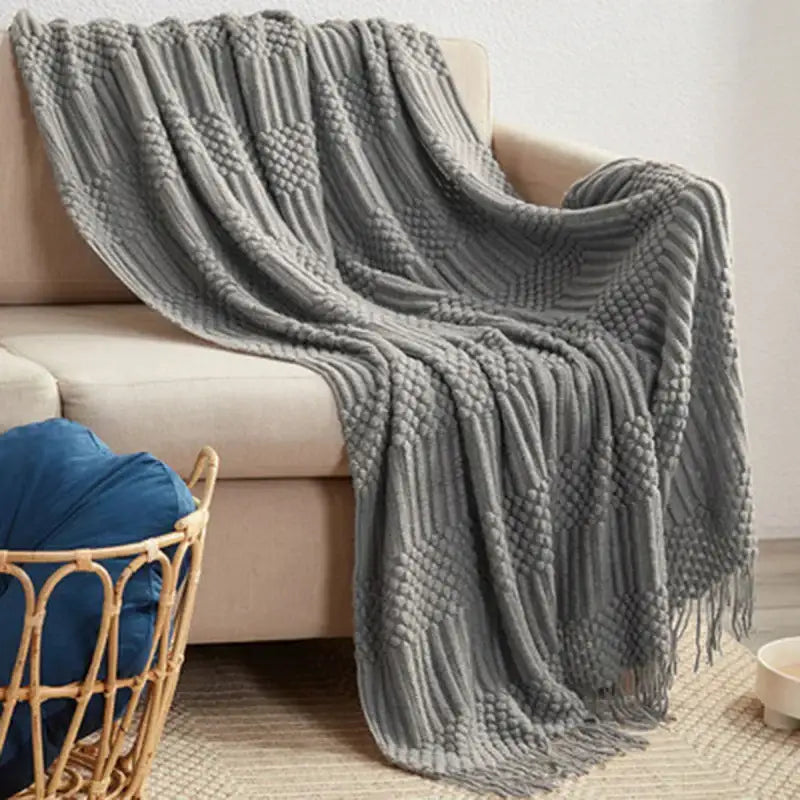 A cozy gray decorbites 3d knitted tassel blanket with ribbed texture and fringe detailing for bedroom decor