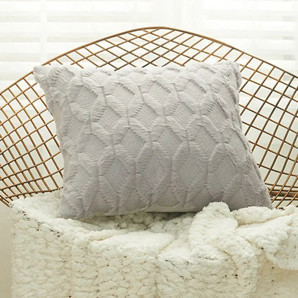 A soft beige off-white cushion cover with a plush geometric diamond pattern resting on a wire chair