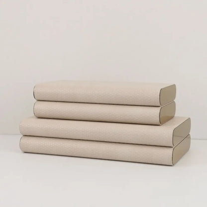 Stack of four beige leather jewelry box storage containers with textured covers and silver hinges by decorbites beige leather