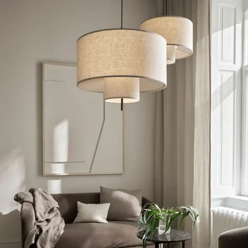 Beige linen handmade fabric chandelier with tiered cylindrical shades hanging in a modern dining room pendant light decorbites handmade fabric