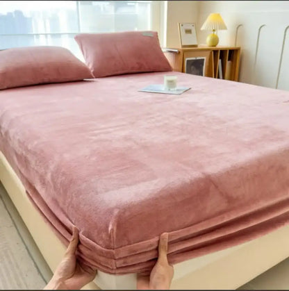 A soft dusty rose fleece bedspread with plush texture shown alongside a beige milk velvet fitted sheet for mattress topper