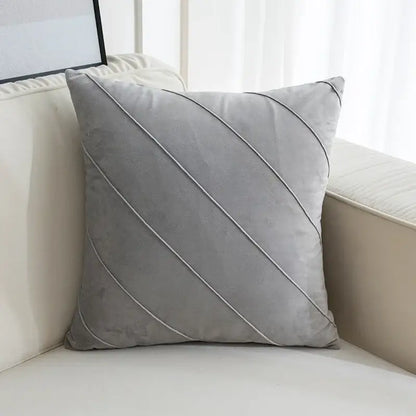 A soft gray velvet throw pillow with diagonal stitched lines featuring hand pleat embroidered detailing for living room use