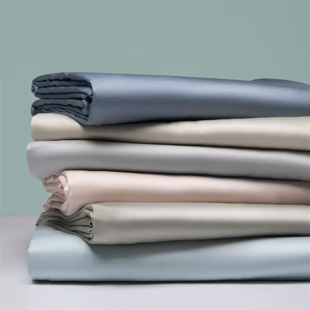 Stack of neatly folded beige satin fitted sheets in soft pastel tones made from decorbites 1000tc egyptian cotton
