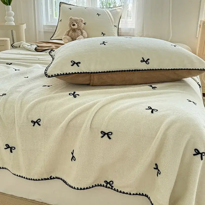 Beige scalloped cozy coral fleece blanket with black embroidered bow decor for bedroom use by decorbites cozy coral