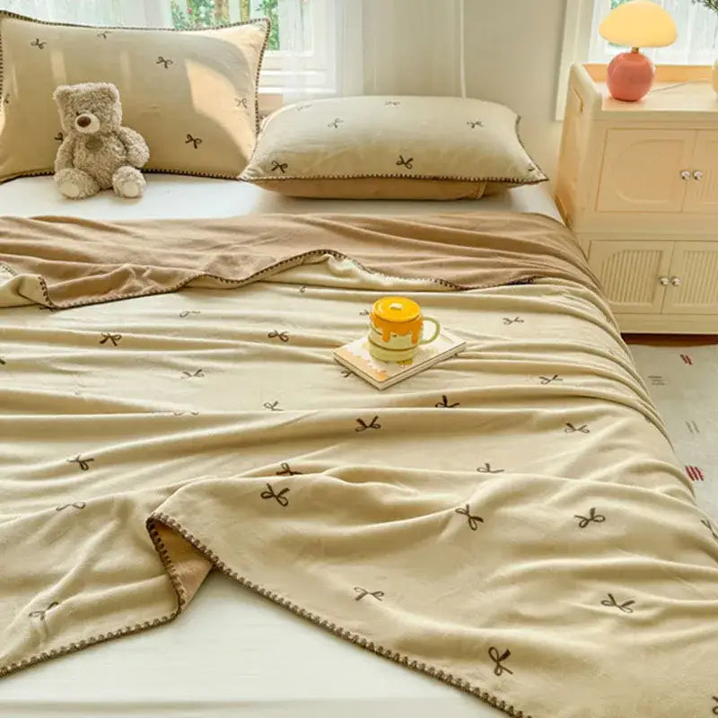 Beige scalloped cozy coral fleece blanket with subtle brown bow decor and stitched edge for bedroom use