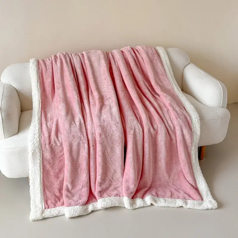 A soft pink fleece blanket with plush white sherpa border draped on a white sofa decorbites cozy lamb wool blanket