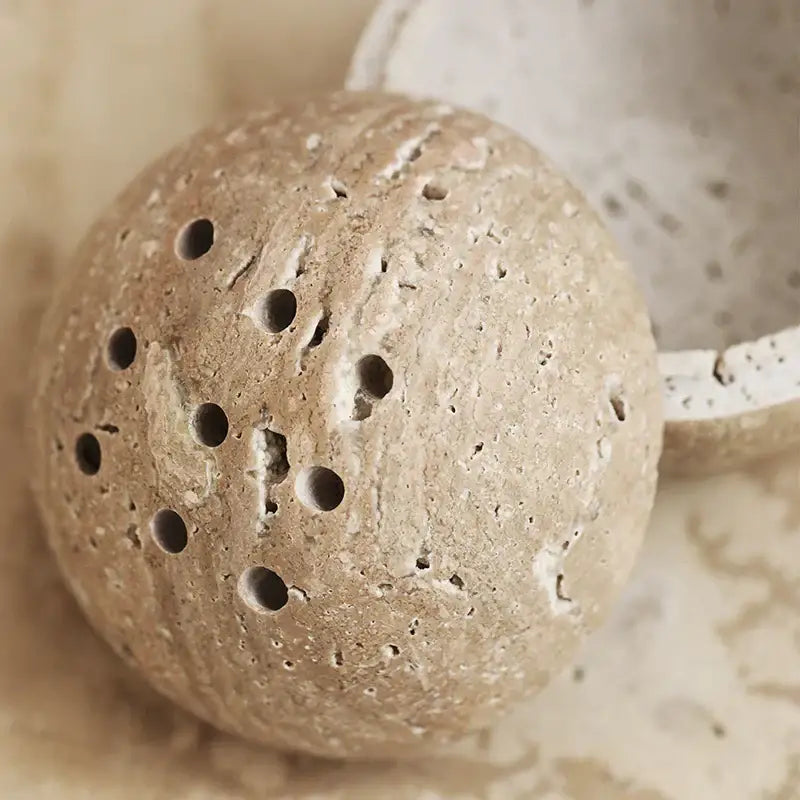 Beige travertine marble incense burner with textured stone and circular holes for living room decor by decorbites