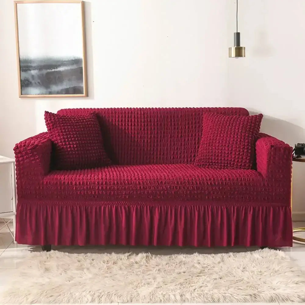 Deep red textured cozy sofa cover with ruffled hem and matching pillows for a living room slipcover