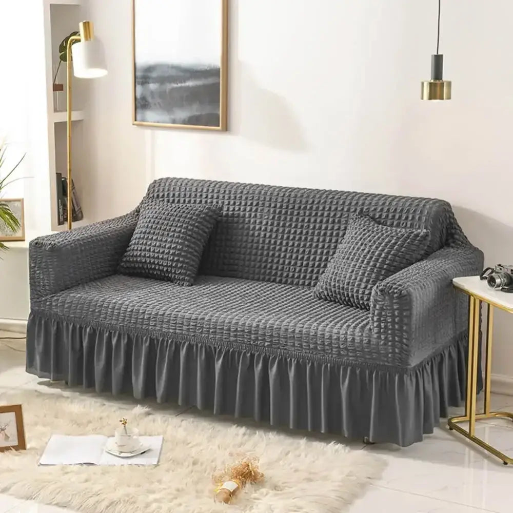 Gray textured stretch sofa cover with ruffled hem and matching pillows as cozy solid color slipcover for living room