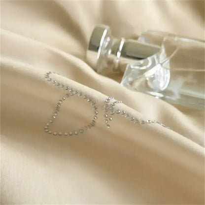A beige and white hot diamond lace bedding set featuring a delicate silver rhinestone o embellishment on satin fabric