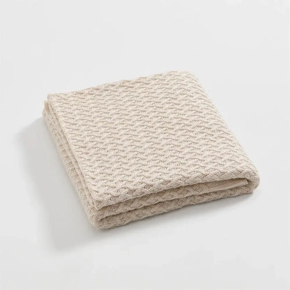 A neatly folded beige knitted bamboo throw blanket with a waffle pattern for decorbites cool summer air conditioning