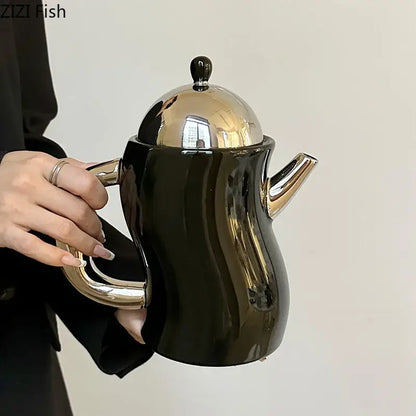 Black ceramic teapot with shiny gold lid handle and spout from decorbites bending design ceramic coffee set