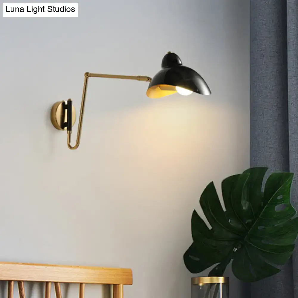 Black matte wall lamp with brass duckbill adjustable joint and circular base emitting warm light for reading