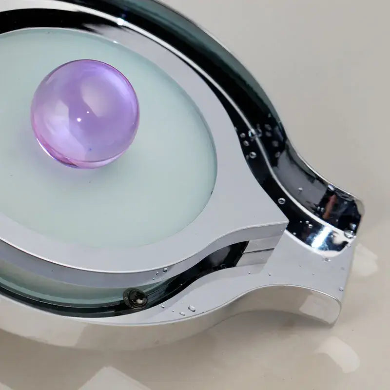 A sleek chrome-finished eyeglass frame with translucent light green lens and purple gemstone complementing decorbites brass led basin faucet