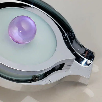 A sleek chrome-finished eyeglass frame with translucent light green lens and purple gemstone complementing decorbites brass led basin faucet