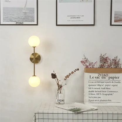 Gold-toned wall lamp with dual spherical glass shades for bedroom decorbites golden glass led sconce design