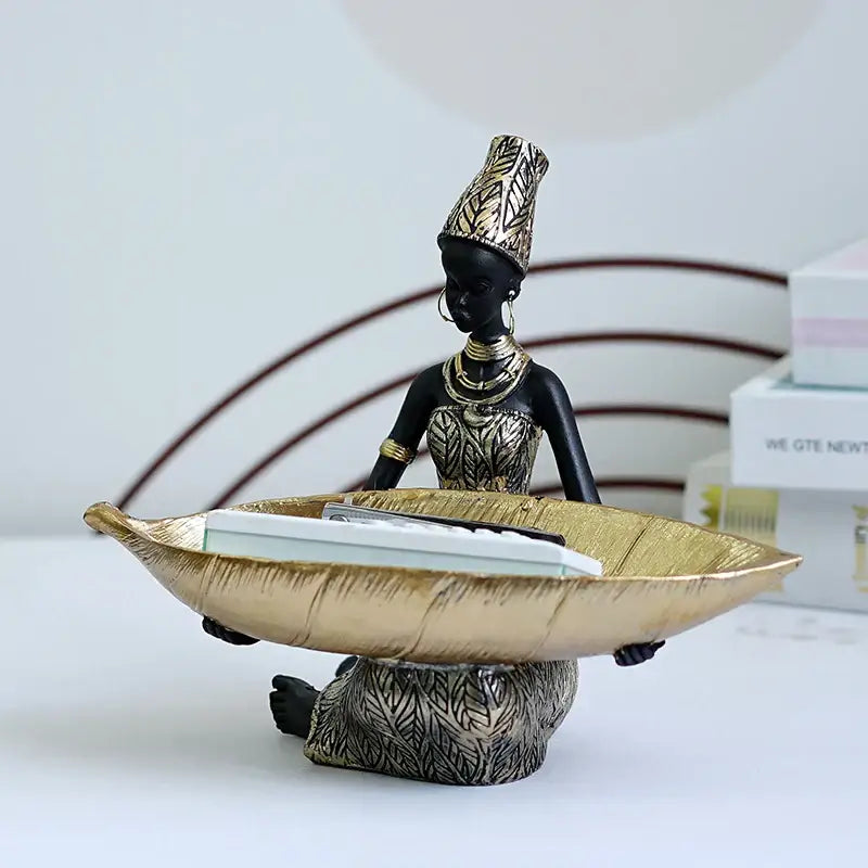 Black and gold resin black woman figurine holding a leaf-shaped living room tray for decorbites black woman decor