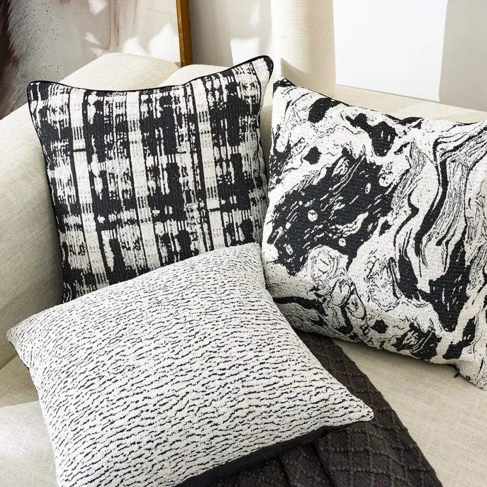 Three black and white geometric chenille pillow covers with abstract woven patterns on a light sofa decorbites pillow cover