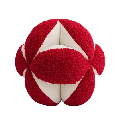 A plush red and white textured spherical toy paired with a black and white jungle plant raccoon pillow cover decorbites decor