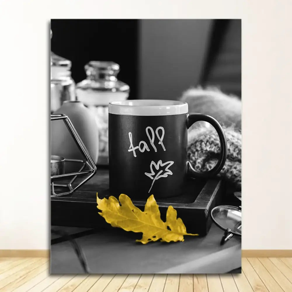 Black ceramic mug with white fall lettering and leaf design beside yellow leaf in DecorBites™ nordic landscape canvas set
