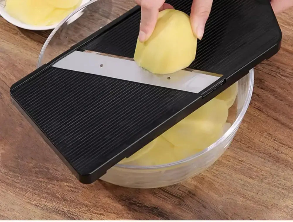 Black and silver decorbites cabbage grater kitchen slicer with hand slicing a potato into thin rounds using mandoline blade