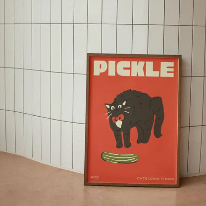 A framed decorbites™ canvas wall art with a bold red background featuring a funny black cat holding a pickle